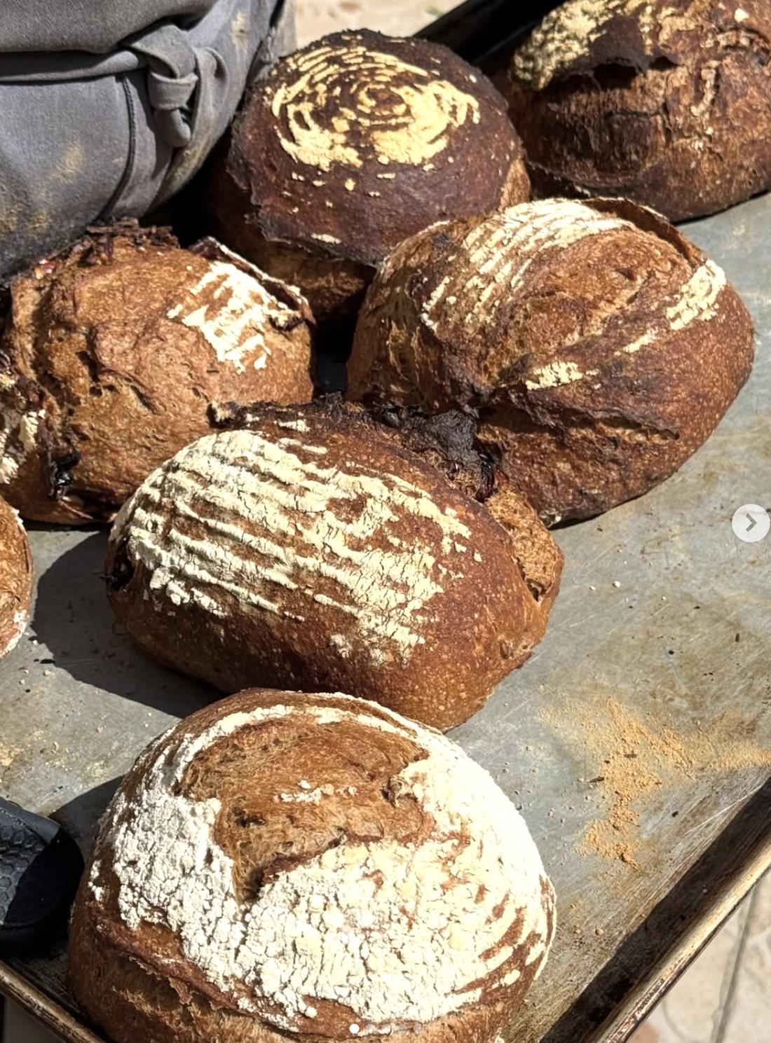 Charola de hogazas de pan de masa madre recién horneadas con greñado marcado en la panadería Asbaje en Toluca